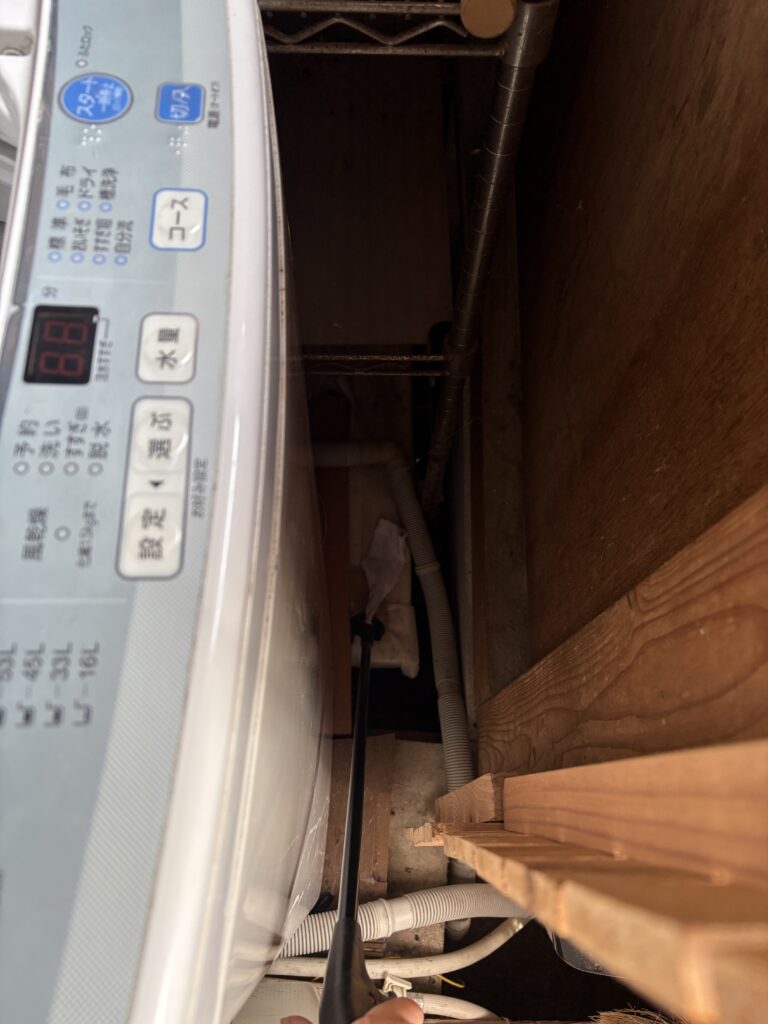 洗濯機横の隙間に落ちた靴下をハンドキャッチャーで拾う様子