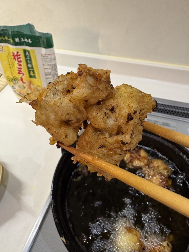 揚げたフグの天ぷらを菜箸で取り出している様子