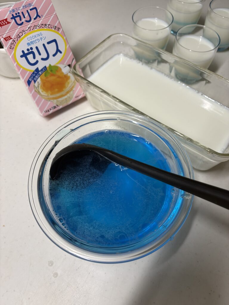 牛乳寒天をガラス容器に流し入れた後の様子とブルーハワイシロップでゼリー液を作る様子