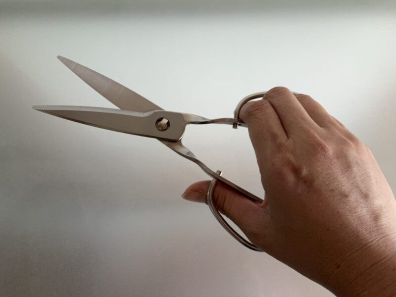 鳥部製作所の日本製ステンレスキッチンバサミを手に持っている様子